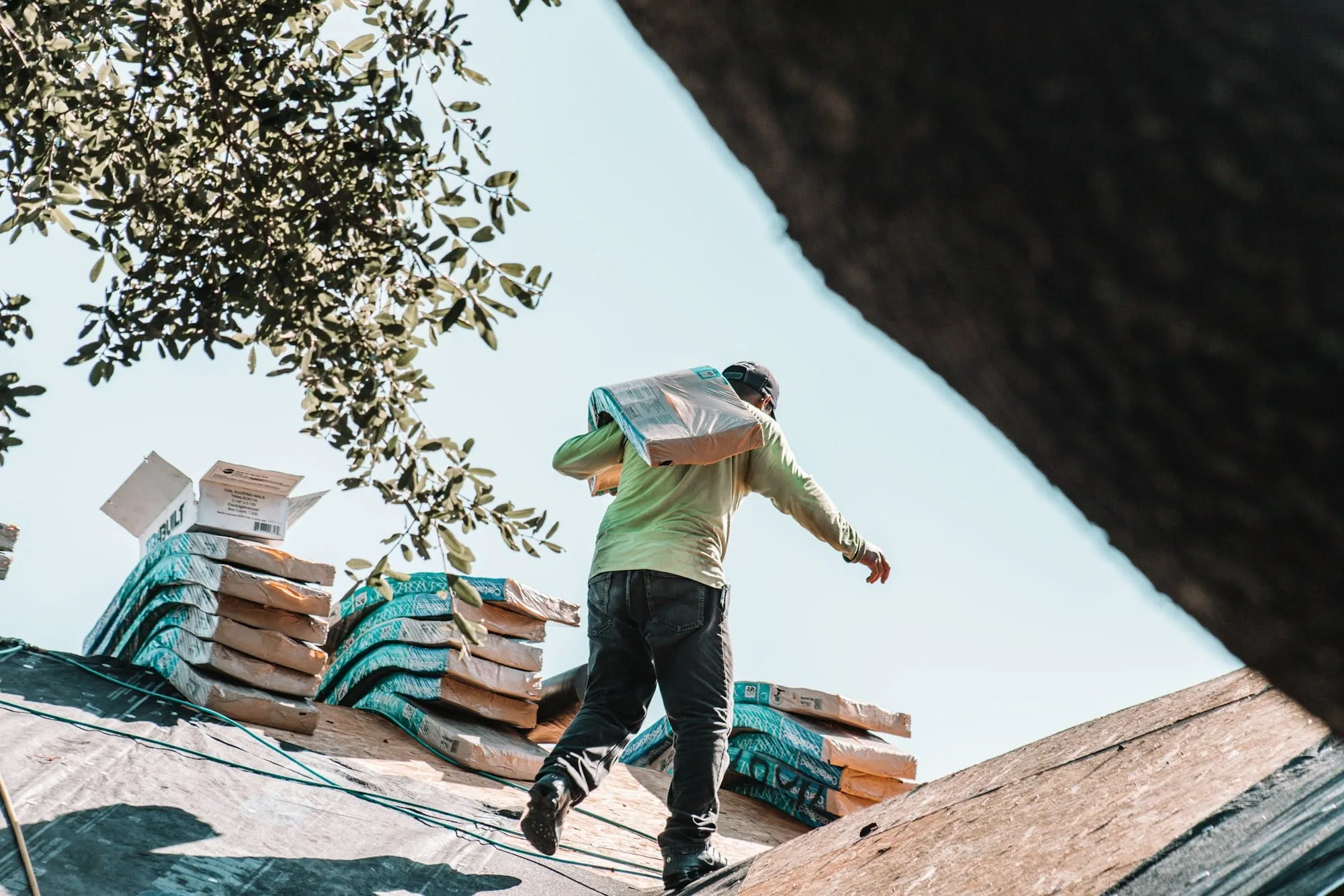 Roofer carrying bundles of shingles
