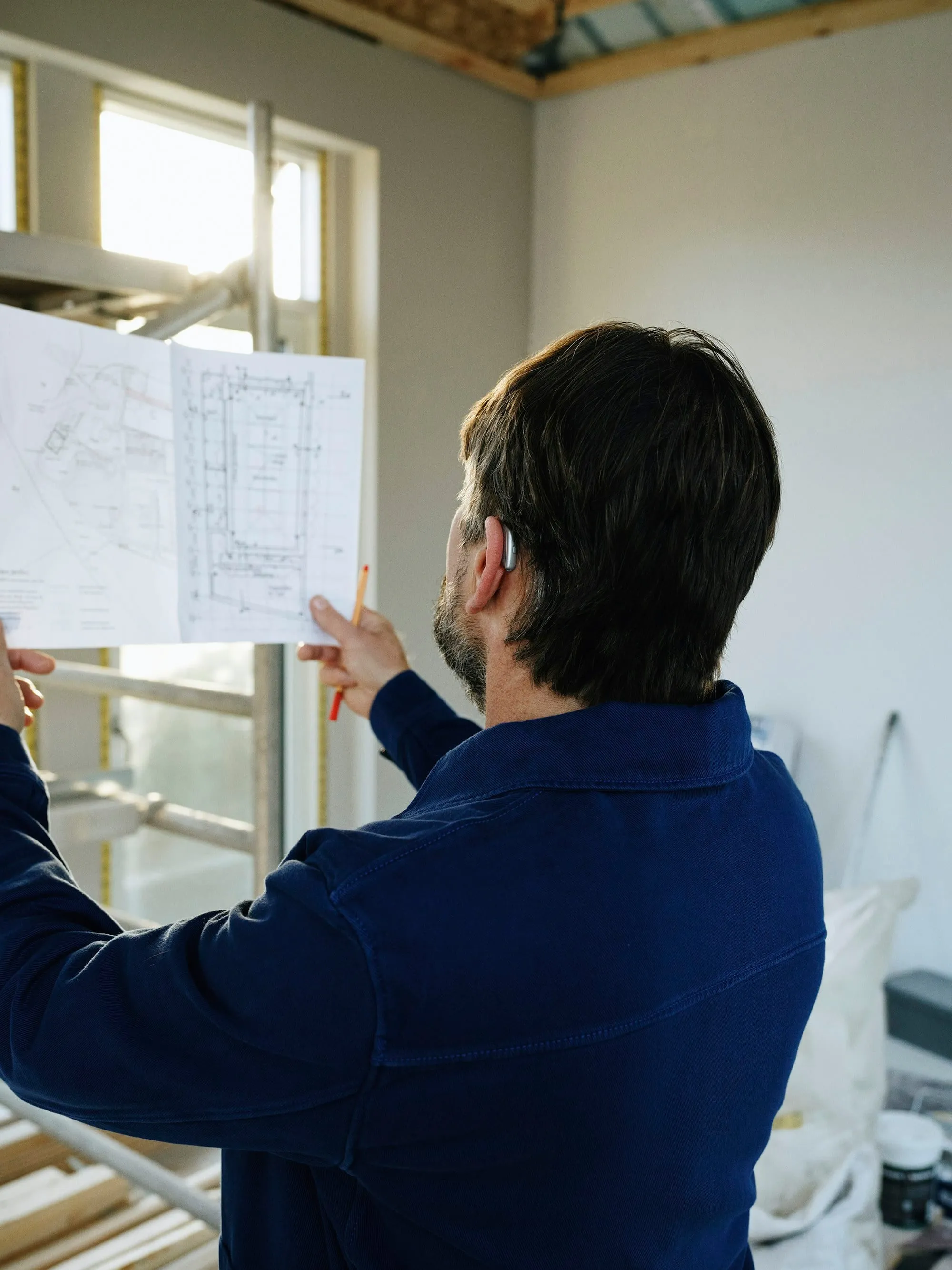 Builder reviewing architectural plans on site