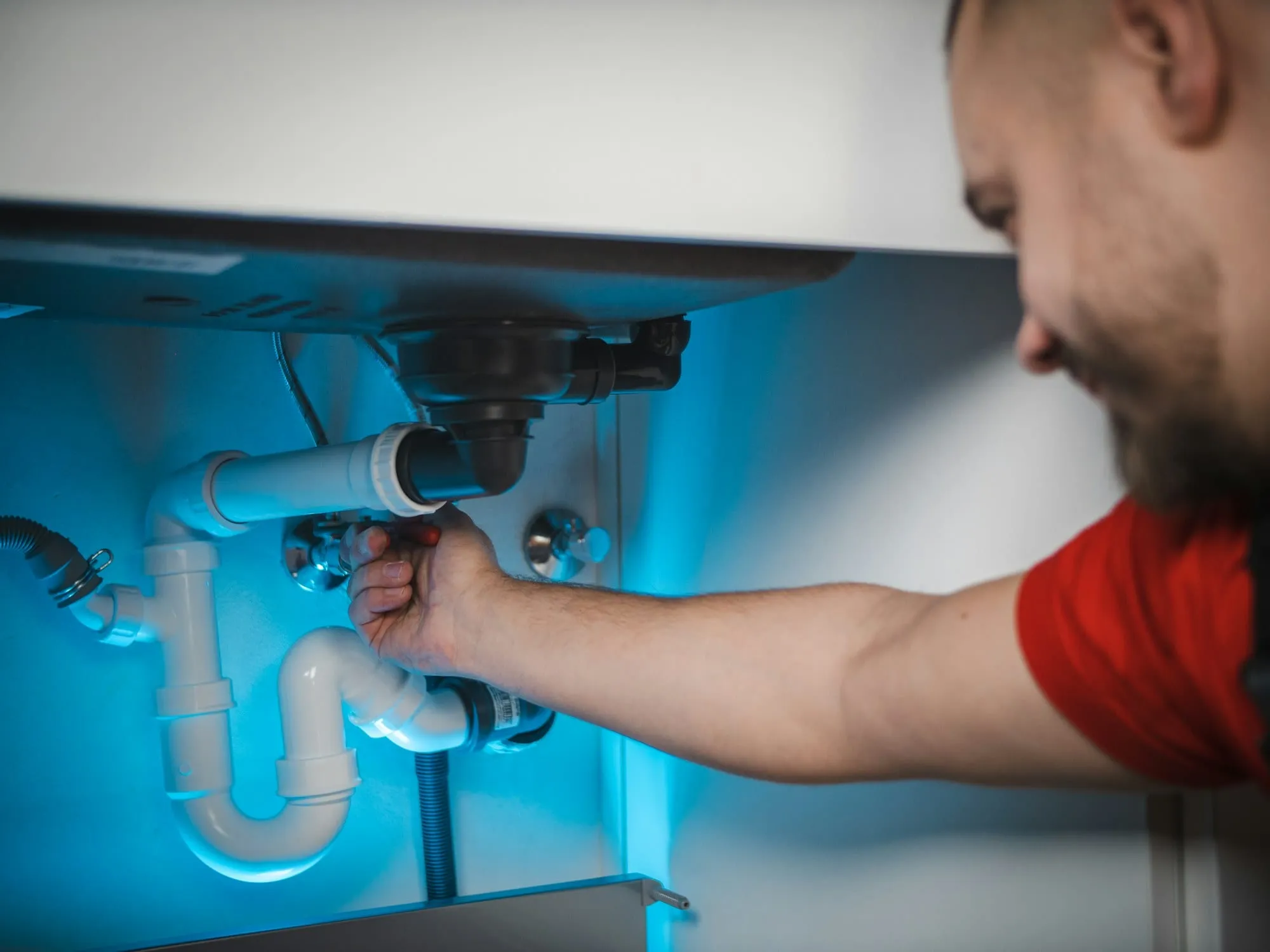Plumber repairing a drain pipe under a sink